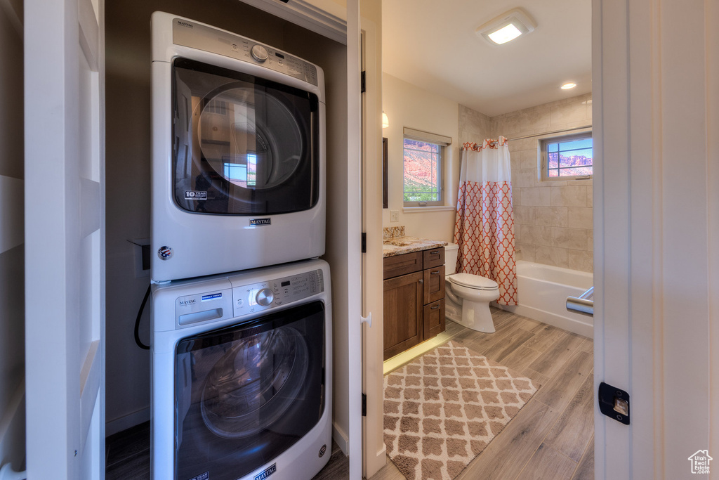Laundry room featuring estacked washer and dryer and light wood-style flooring