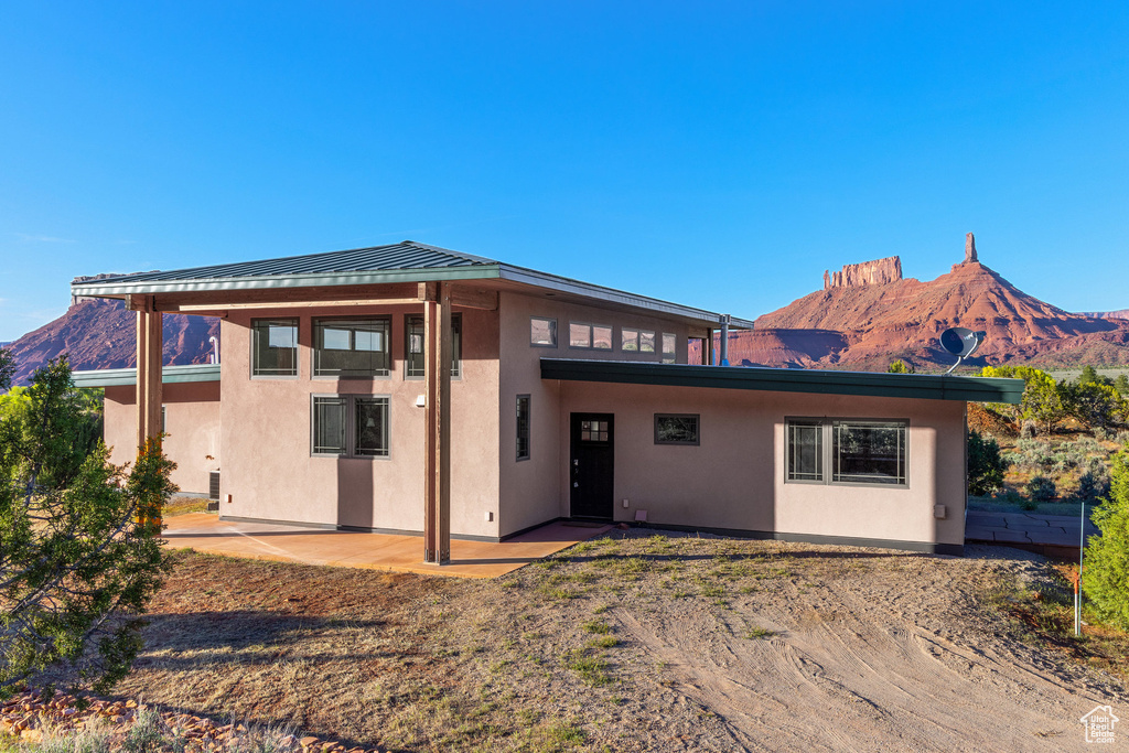Rear view of property with a mountain view, stucco siding, and a patio area