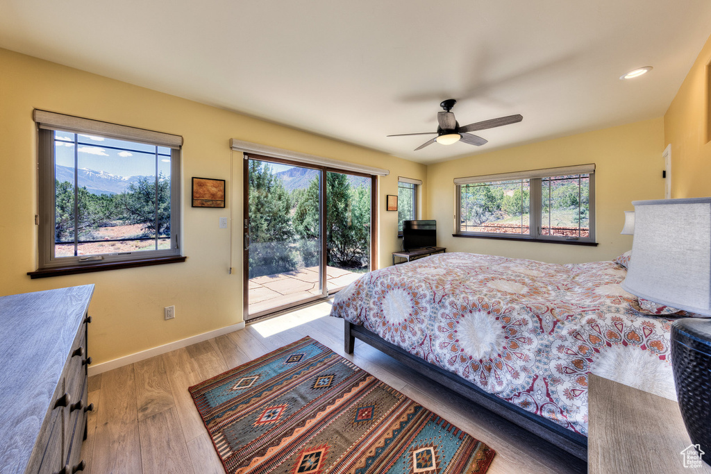 Bedroom featuring access to outside, wood finished floors, baseboards, and a ceiling fan
