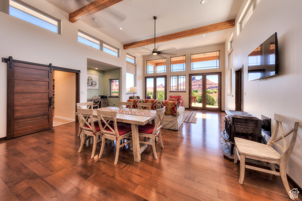 Dining room with beamed ceiling, a barn door, plenty of natural light, hardwood / wood-style flooring, and a ceiling fan