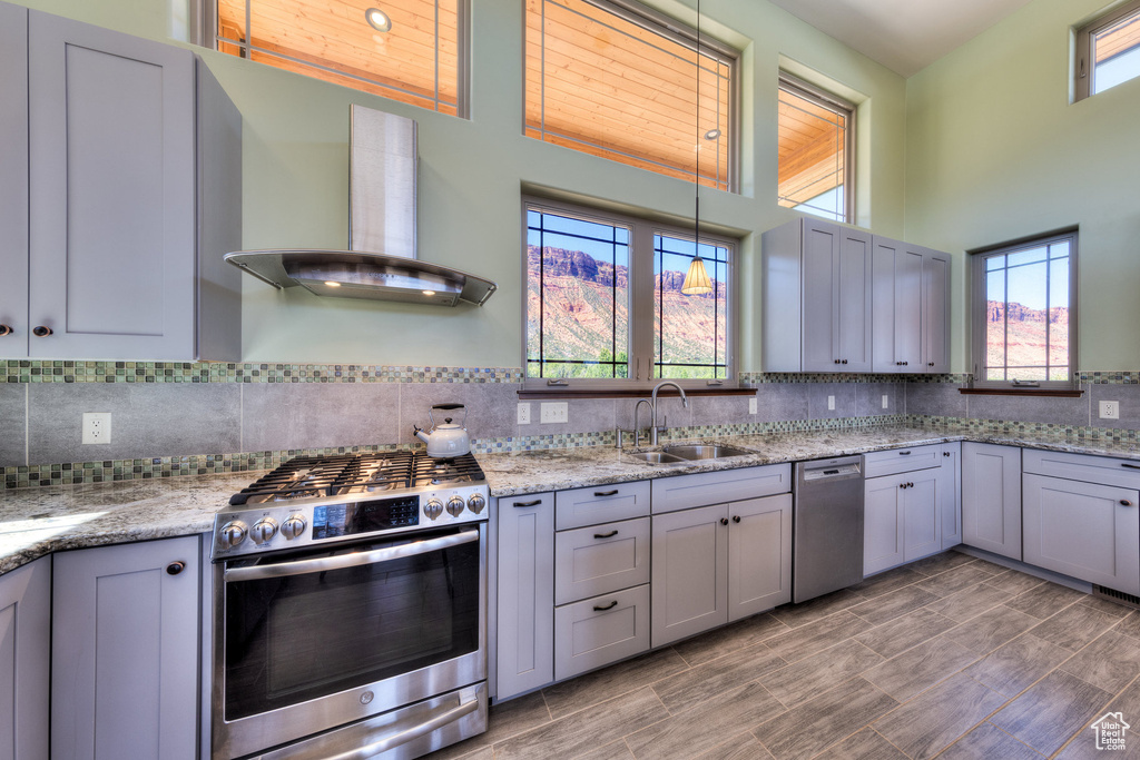 Kitchen with stainless steel appliances, a sink, wall chimney exhaust hood, tasteful backsplash, and plenty of natural light