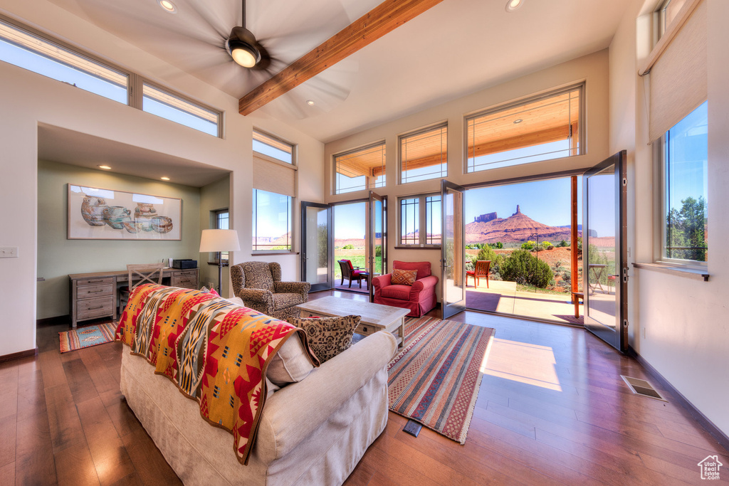 Living area with dark wood-type flooring, a high ceiling, a mountain view, beam ceiling, and recessed lighting
