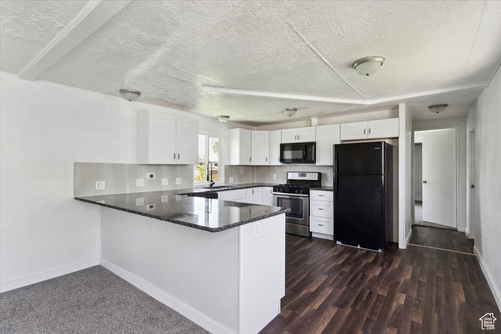 Kitchen with black appliances, a peninsula, white cabinetry, baseboards, and a textured ceiling
