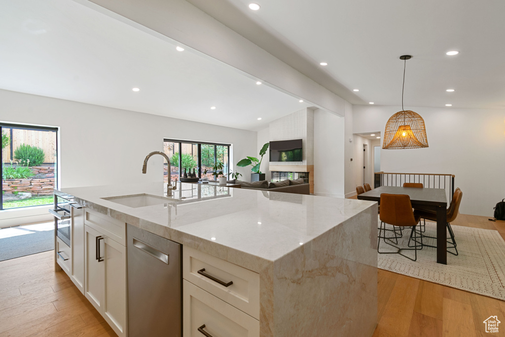 Kitchen featuring stainless steel dishwasher, light stone counters, light wood-type flooring, white cabinetry, and recessed lighting