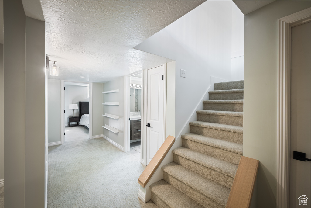 Stairway with carpet floors, a textured ceiling, baseboards, and built in features