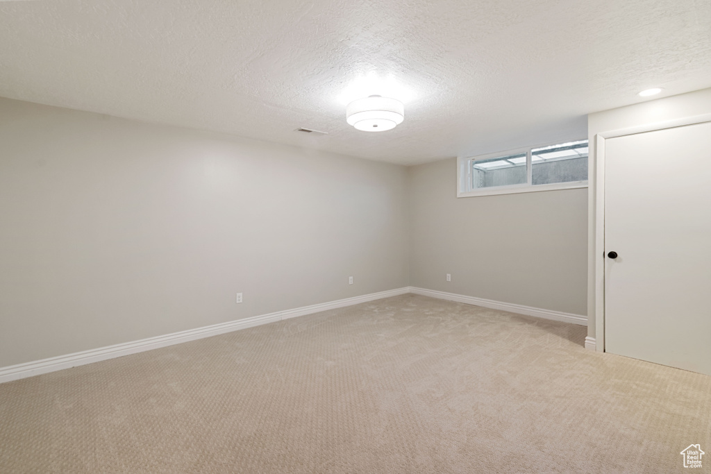 Below grade area with light carpet and a textured ceiling