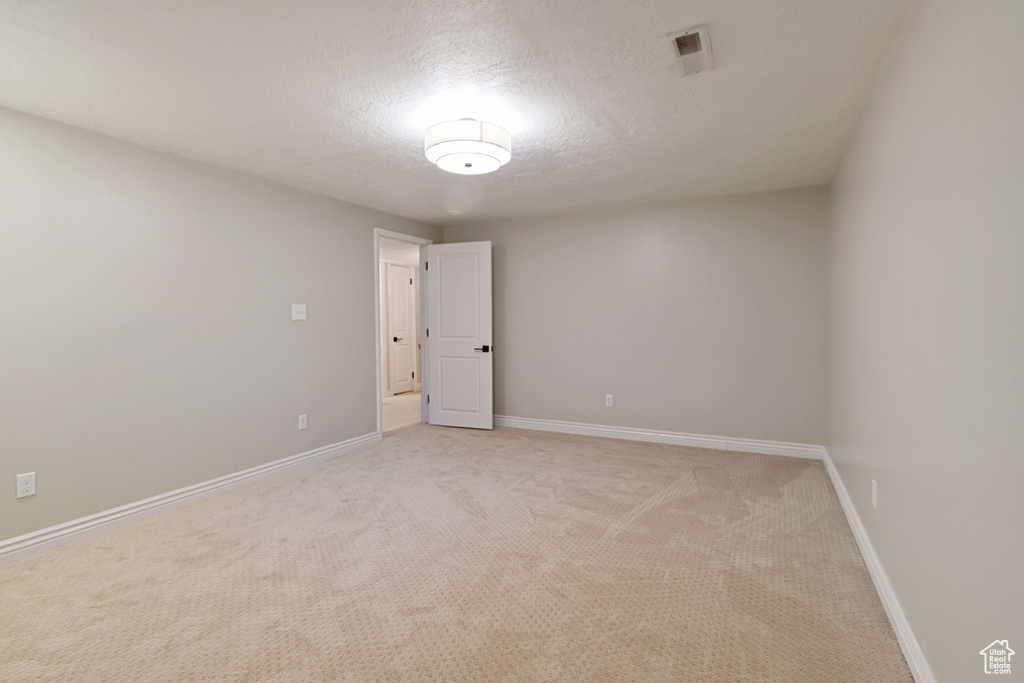 Spare room featuring light colored carpet and a textured ceiling