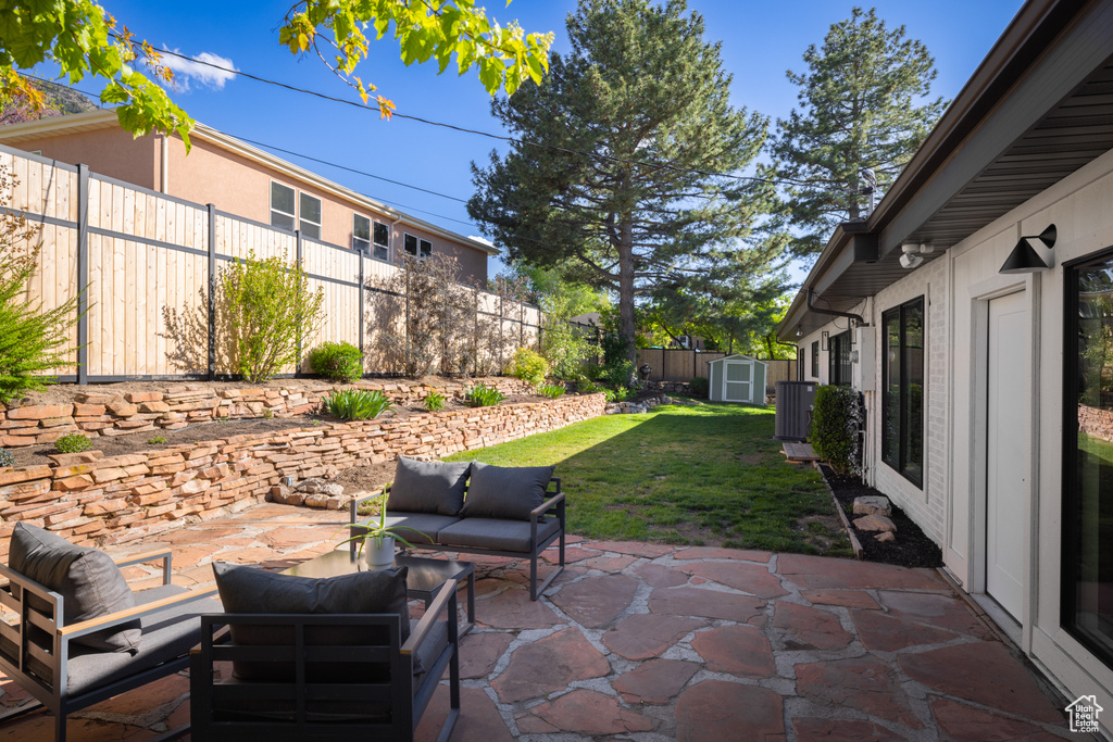 View of patio with a storage unit, an outdoor hangout area, an outbuilding, and central air condition unit