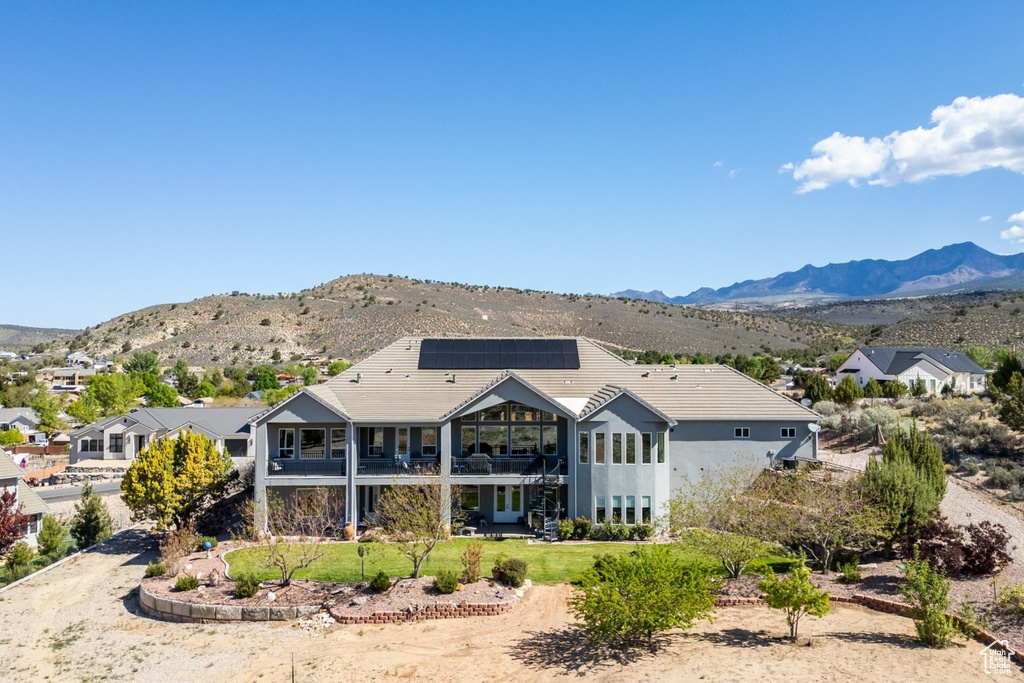 Rear view of house with a balcony, roof mounted solar panels, and a mountain view