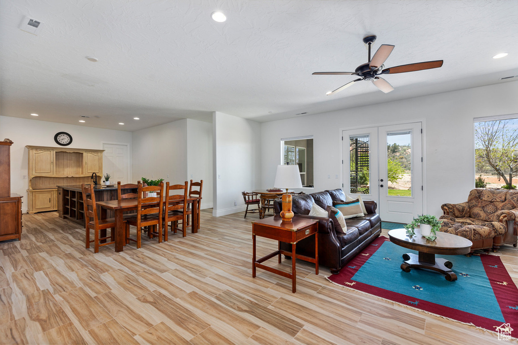Living area featuring recessed lighting, ceiling fan, baseboards, and light wood-style flooring
