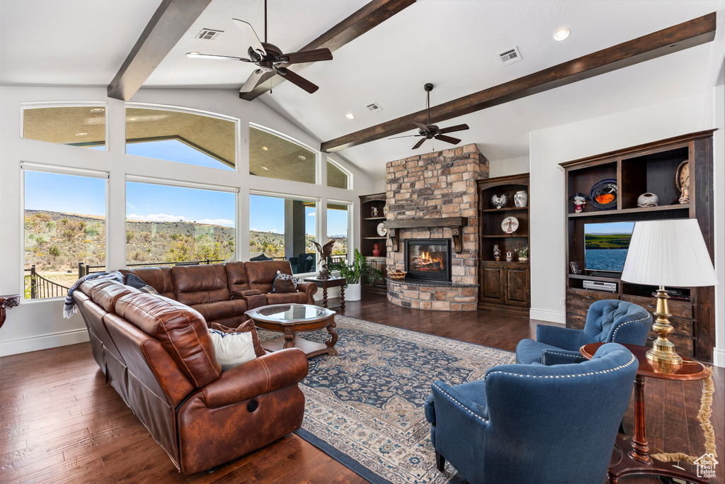 Living area featuring ceiling fan, plenty of natural light, wood finished floors, and a stone fireplace