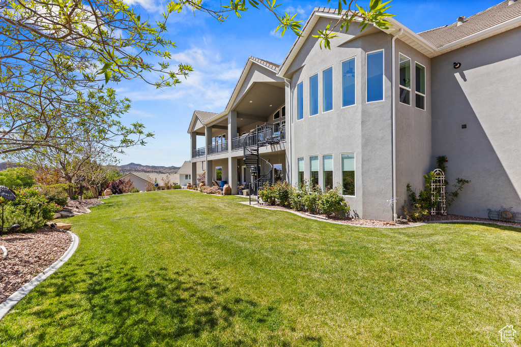 Rear view of property featuring stucco siding, stairway, and a lawn