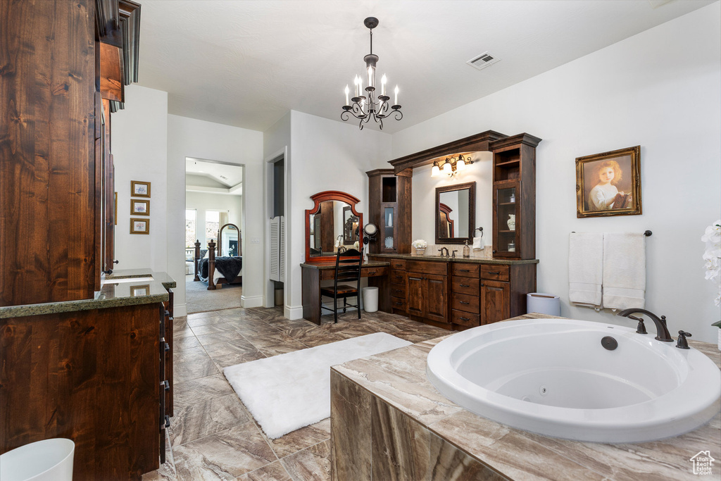 Bathroom featuring a chandelier, a jetted tub, vanity, and marble finish flooring