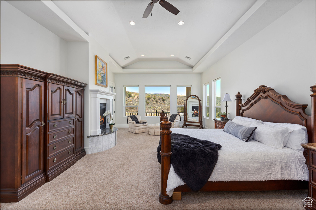 Carpeted bedroom with lofted ceiling, recessed lighting, access to exterior, a warm lit fireplace, and a ceiling fan
