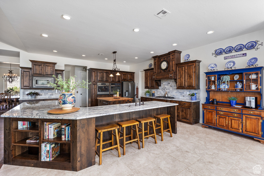 Kitchen featuring open shelves, stainless steel appliances, a spacious island, a sink, and decorative backsplash