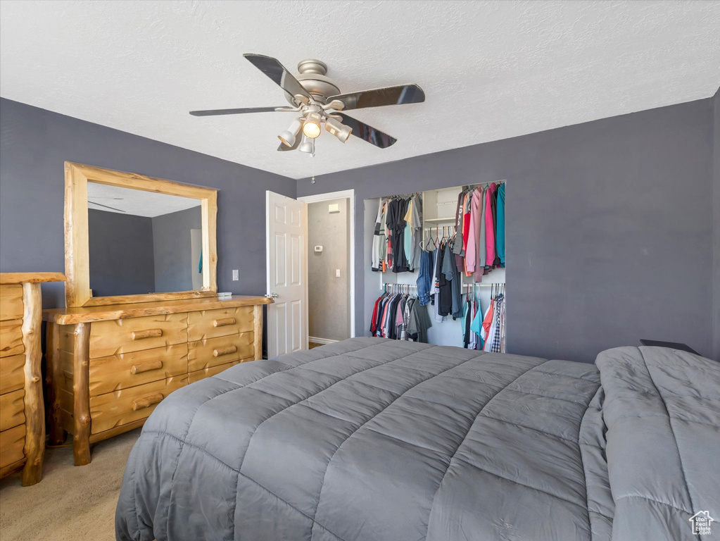 Carpeted bedroom featuring ceiling fan and a closet