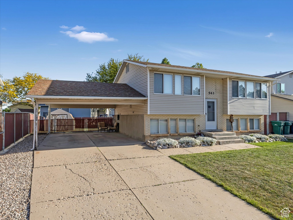 Raised ranch with driveway, a carport, and brick siding