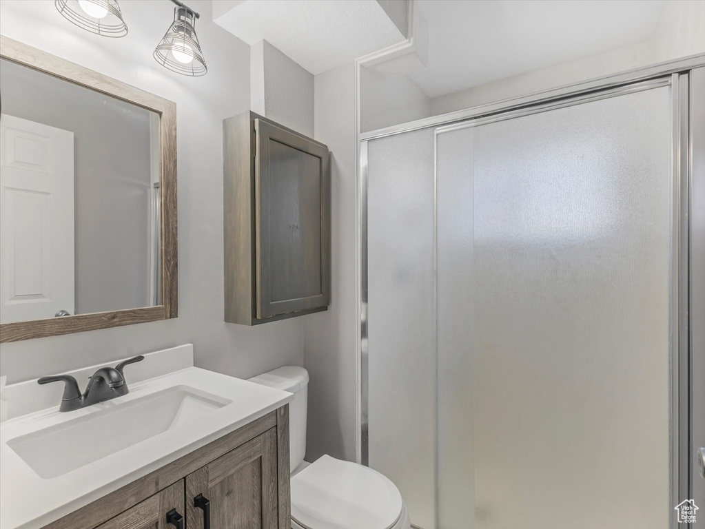 Full bathroom with a stall shower, toilet, and vanity
