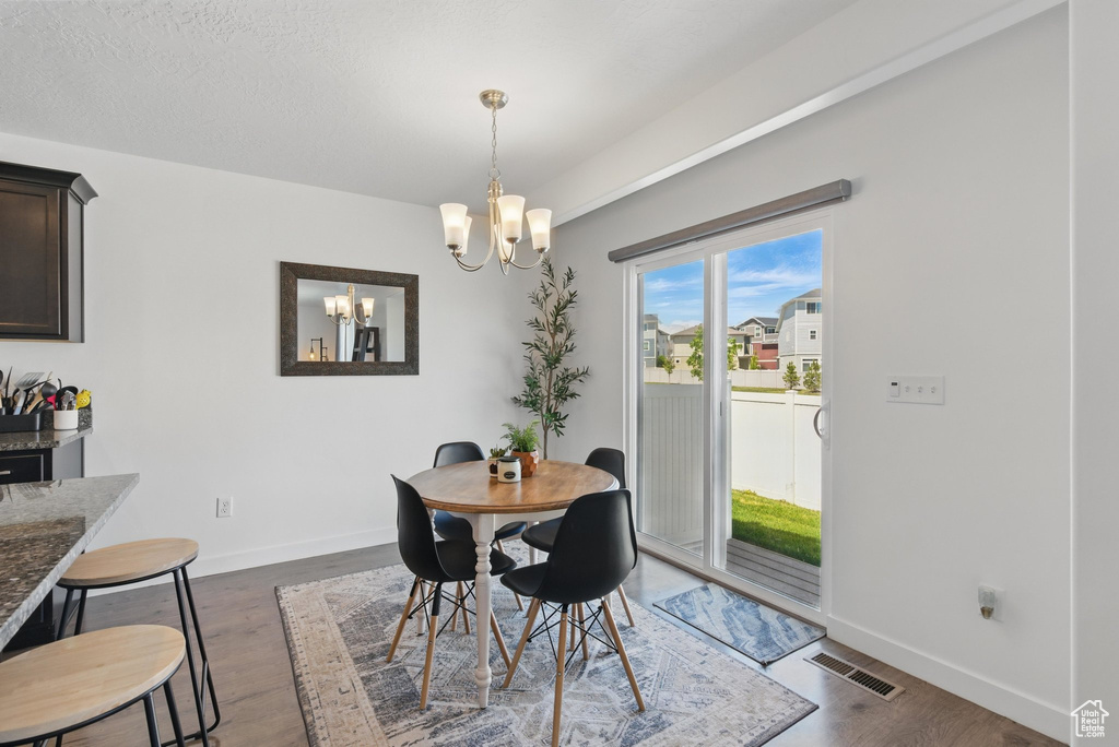 Dining area featuring a chandelier, baseboards, and dark wood-type flooring