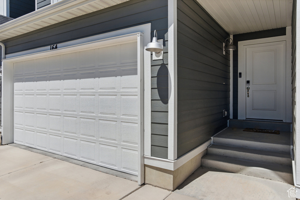View of exterior entry featuring a garage and concrete driveway