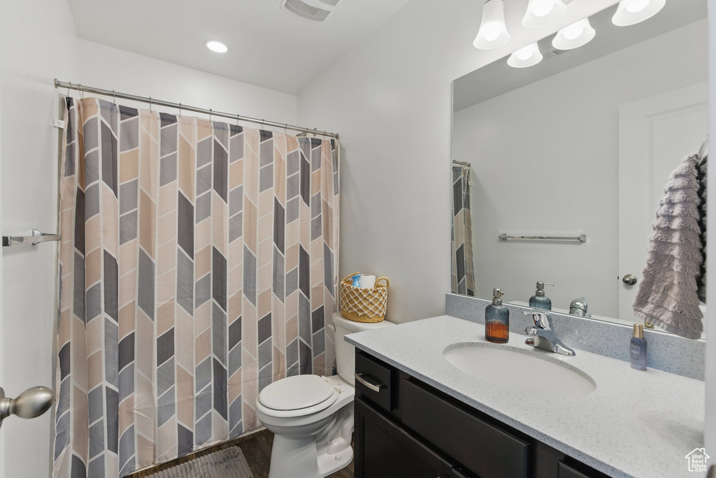Full bath featuring vanity, toilet, wood finished floors, curtained shower, and recessed lighting