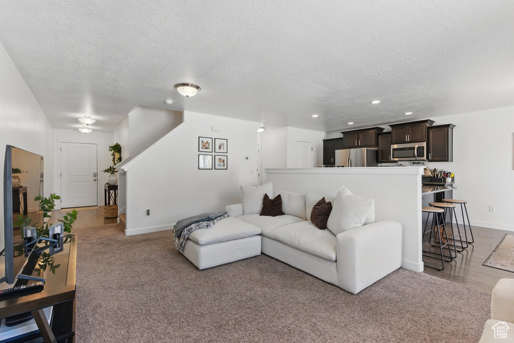 Living area with a textured ceiling, recessed lighting, baseboards, and carpet