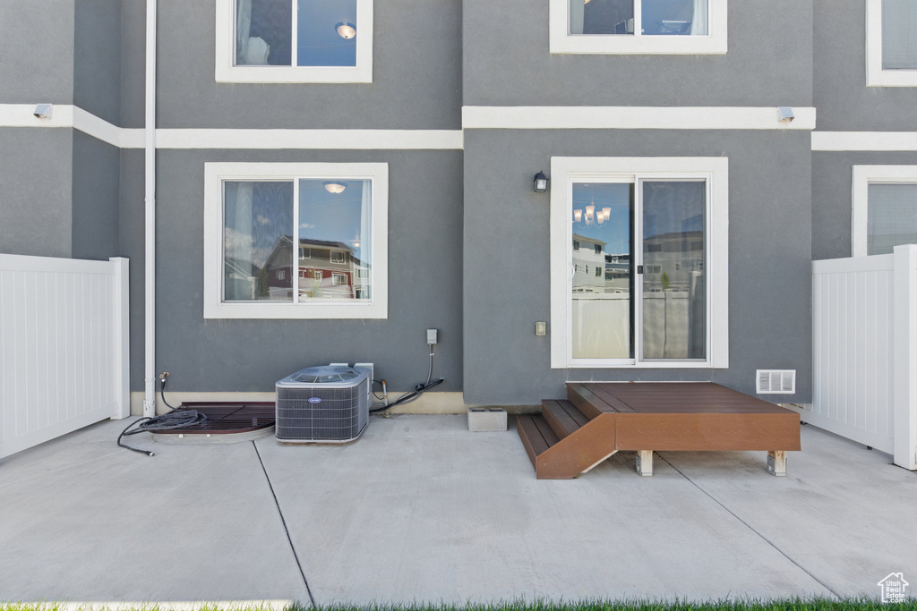 Rear view of house featuring stucco siding, central air condition unit, and a patio area