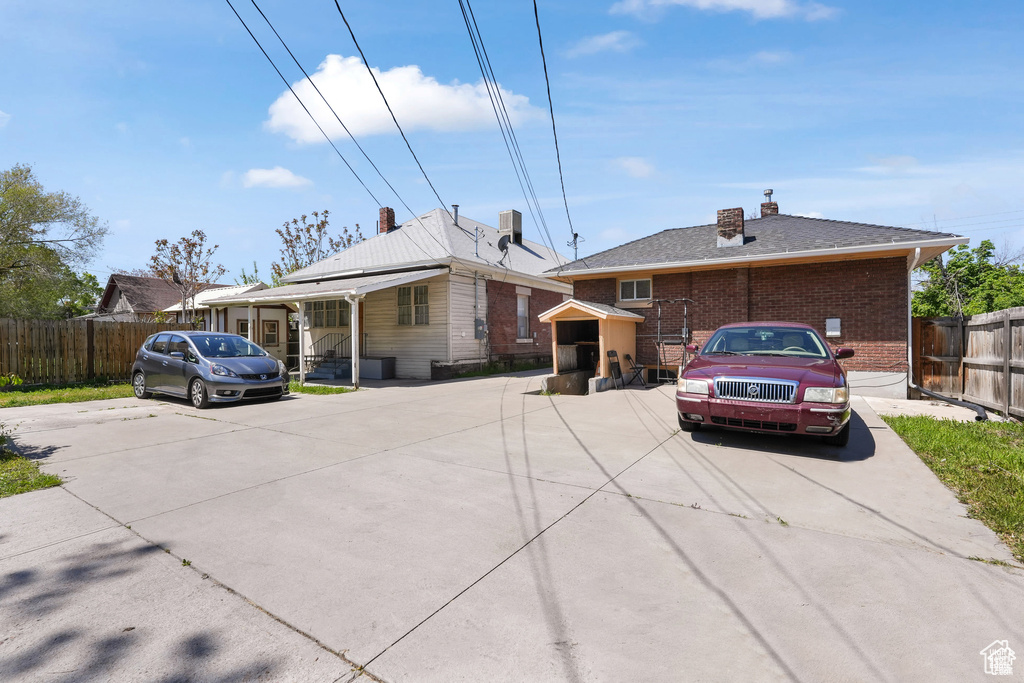 View of front of house featuring brick siding, fence, and a chimney