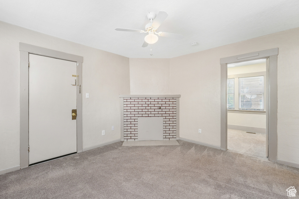 Unfurnished living room featuring ceiling fan, a fireplace with flush hearth, baseboards, and carpet