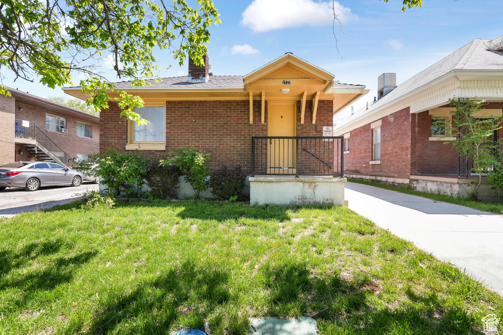 View of front of home with brick siding, a chimney, and a front yard