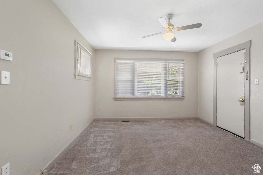 Carpeted empty room with baseboards and a ceiling fan