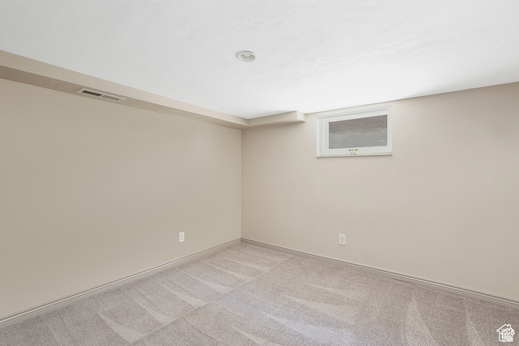 Empty room featuring visible vents, carpet, and baseboards