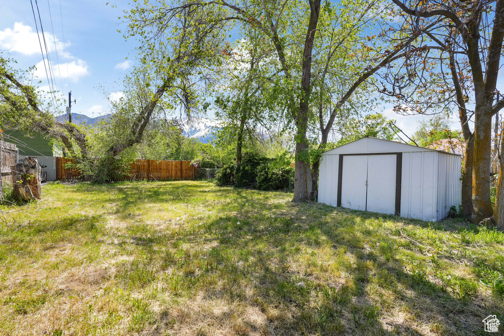 View of yard with an outdoor structure, fence, and a storage shed
