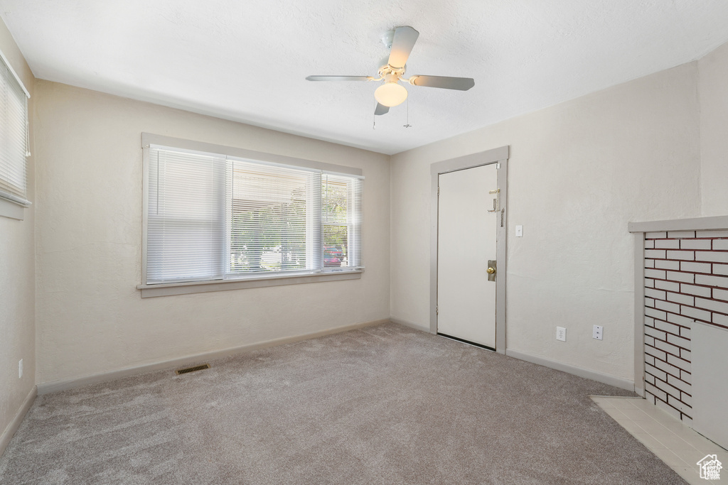 Empty room featuring a ceiling fan, baseboards, visible vents, and carpet