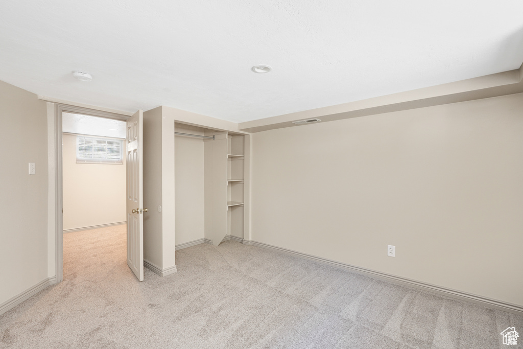 Unfurnished bedroom featuring baseboards, visible vents, a closet, and light colored carpet