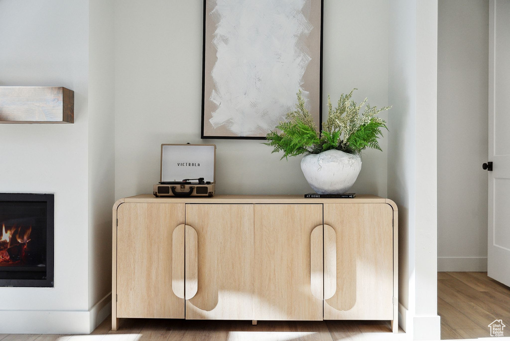 Detailed view of wood finished floors, a warm lit fireplace, and baseboards