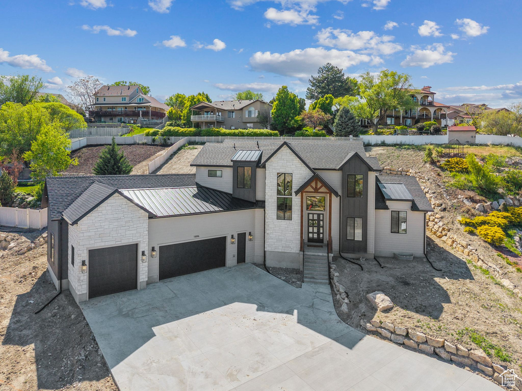 View of front of property with a garage, a standing seam roof, a residential view, concrete driveway, and metal roof