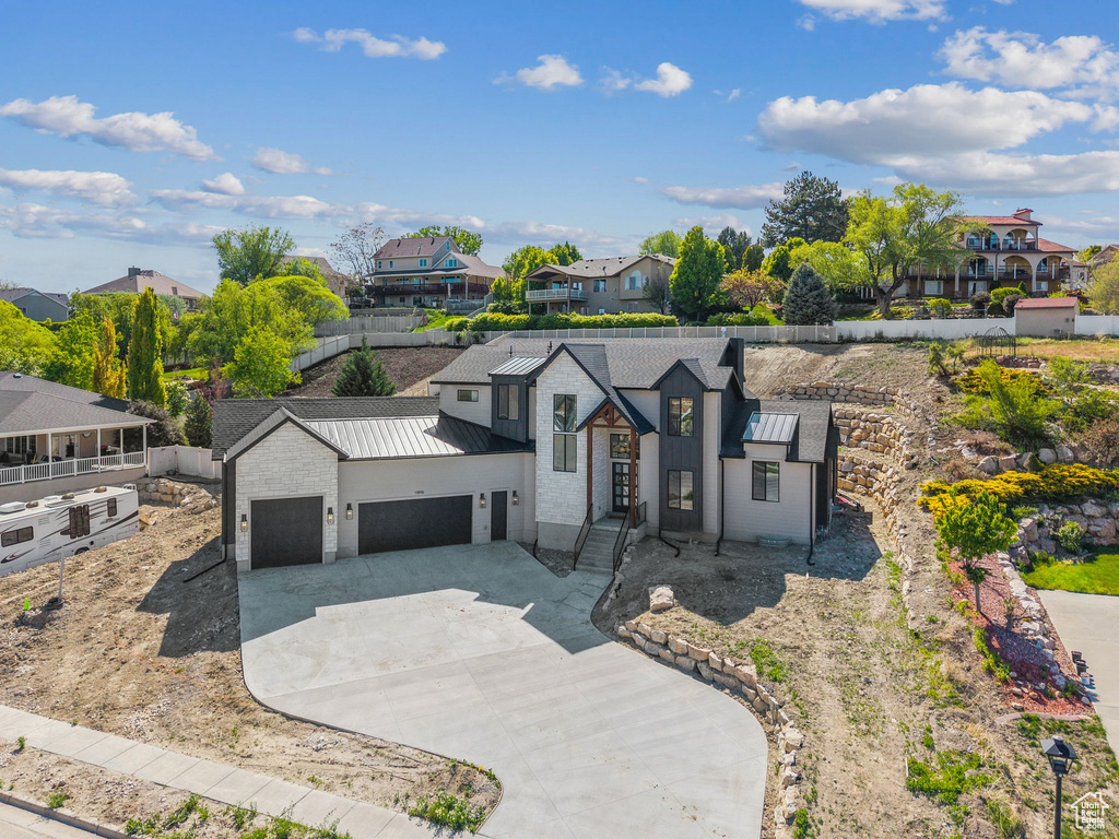 Contemporary home featuring a residential view, an attached garage, a standing seam roof, driveway, and metal roof