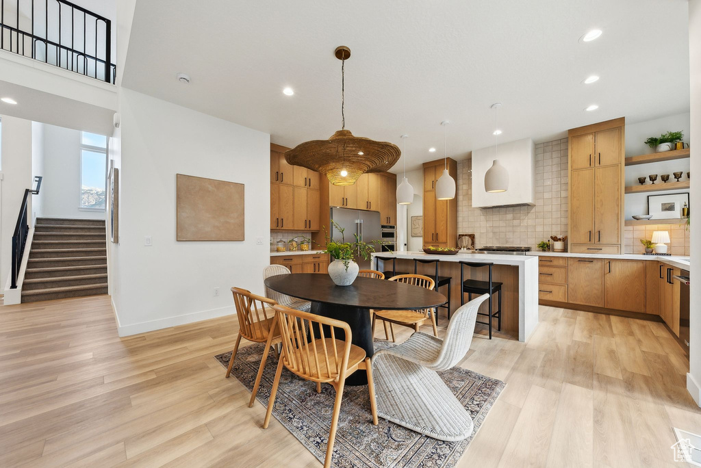 Dining space with recessed lighting, light wood finished floors, stairway, and baseboards