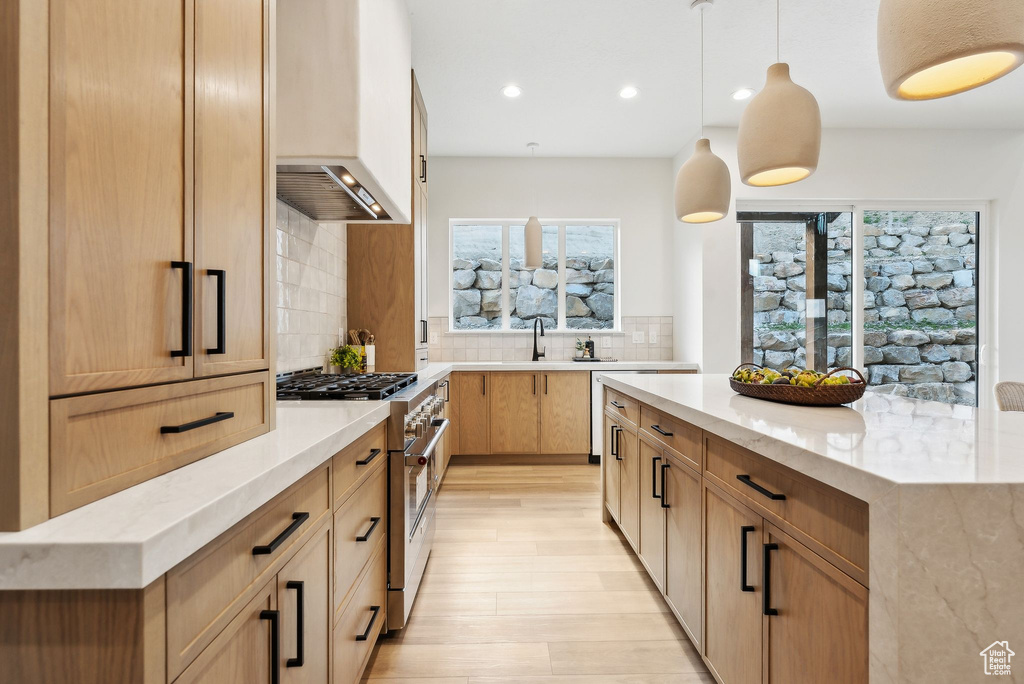 Kitchen with high end range, premium range hood, plenty of natural light, light stone countertops, and recessed lighting
