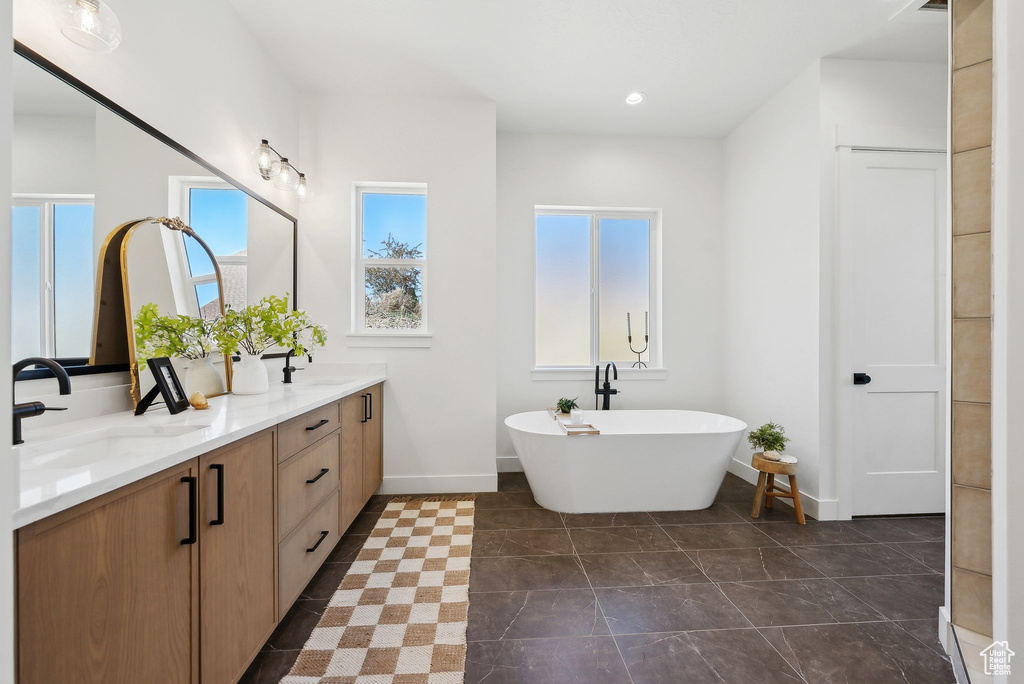 Full bathroom with a freestanding bath, double vanity, baseboards, and recessed lighting