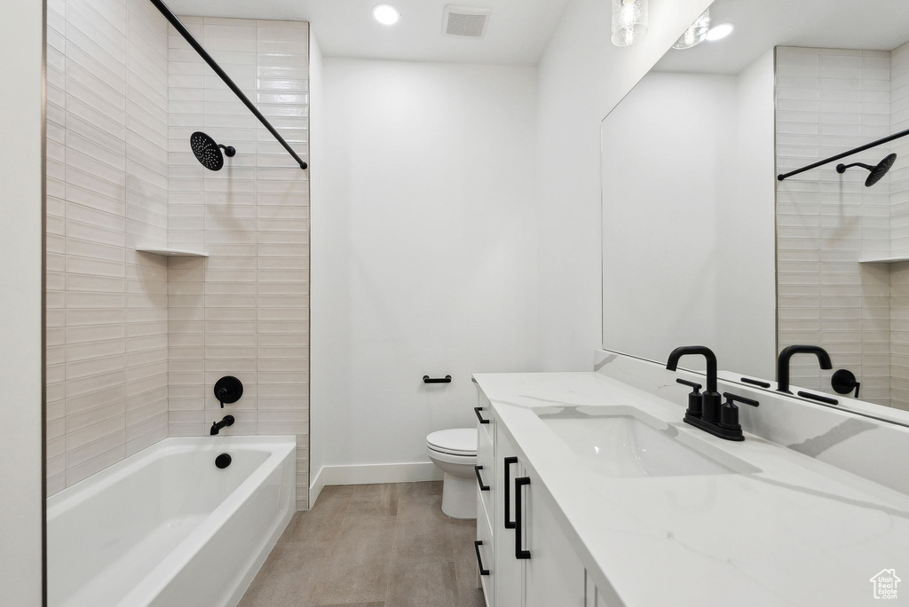 Full bath featuring baseboards, toilet, vanity, wood finished floors, and bathing tub / shower combination