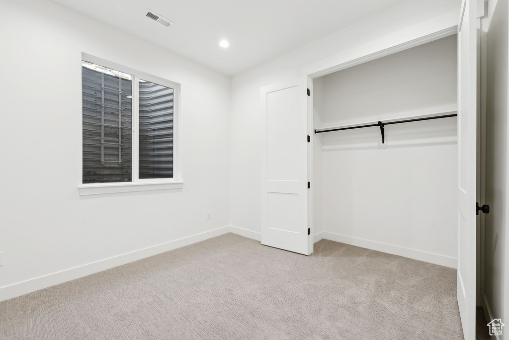 Unfurnished bedroom featuring light carpet, baseboards, recessed lighting, and a closet