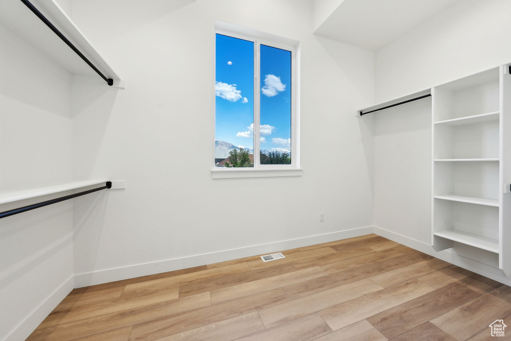Walk in closet with light wood-style flooring