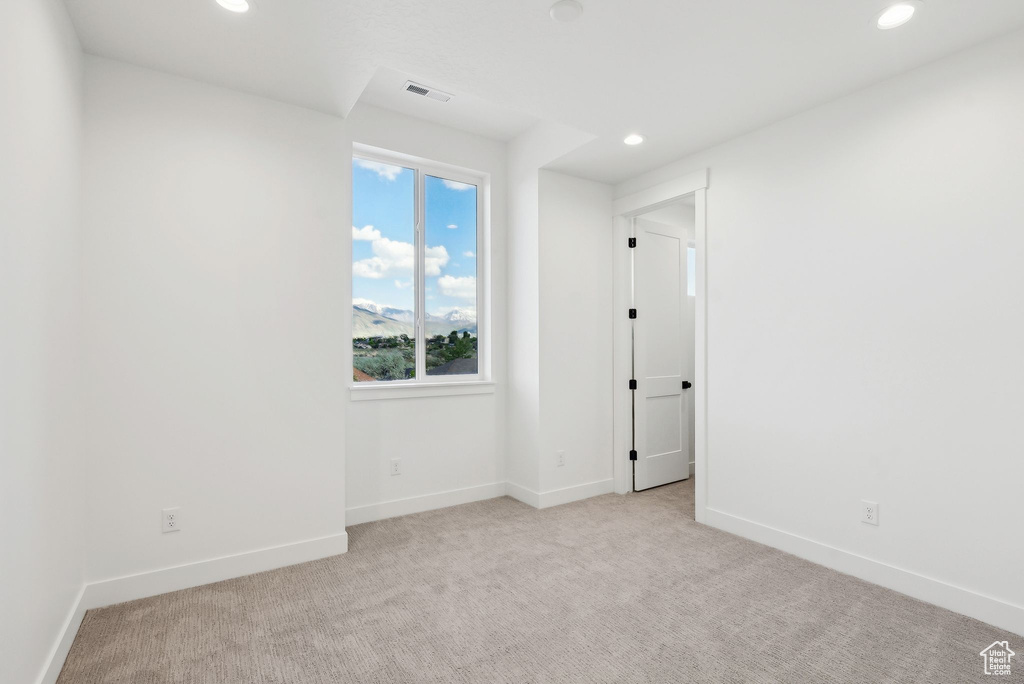 Spare room featuring recessed lighting, light colored carpet, and baseboards