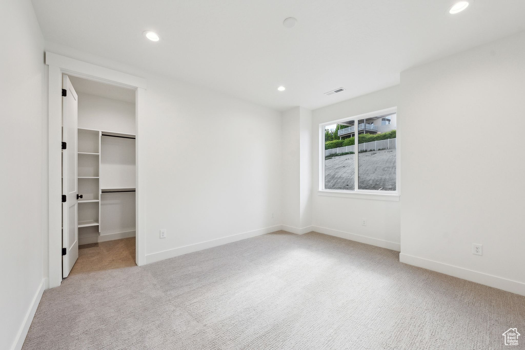 Unfurnished bedroom with carpet floors, recessed lighting, baseboards, and a walk in closet