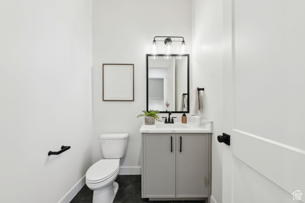 Bathroom with baseboards, toilet, vanity, and tile patterned floors
