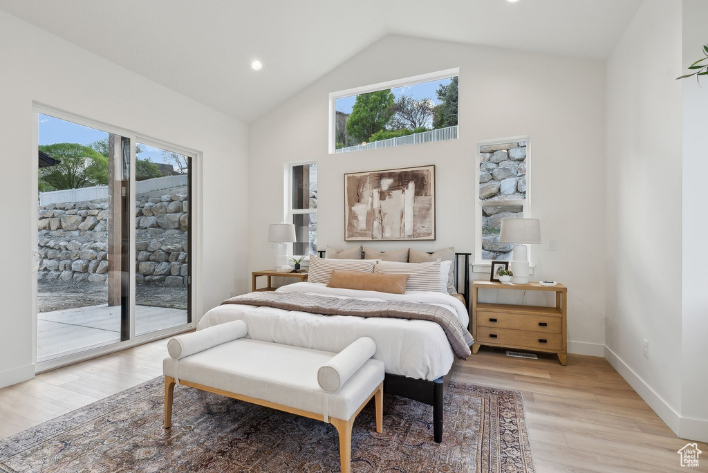 Bedroom featuring access to exterior, multiple windows, light wood-style floors, baseboards, and high vaulted ceiling