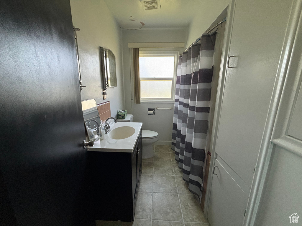 Full bathroom featuring toilet, tile patterned flooring, vanity, and a shower with shower curtain