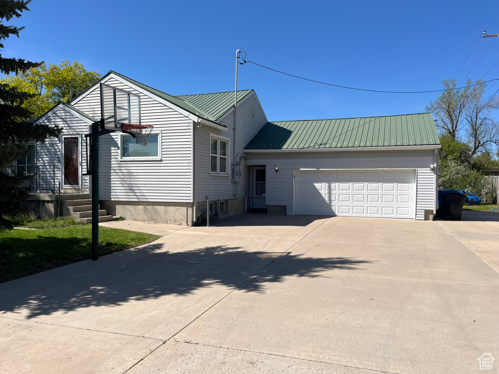View of front of property with a garage, concrete driveway, and metal roof
